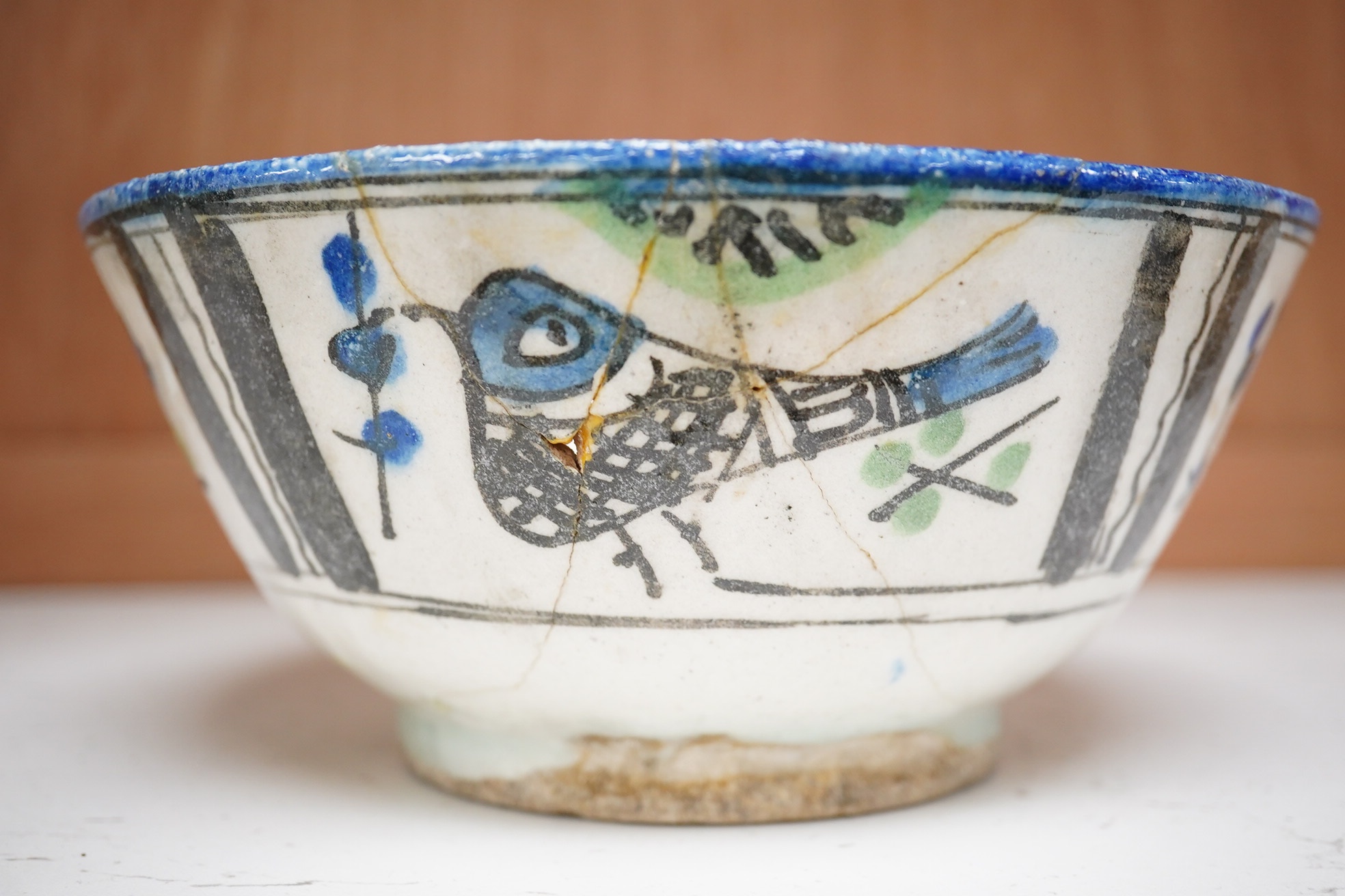 An 18th century Persian pottery bowl with bird decoration, 19cm diameter. Condition - poor